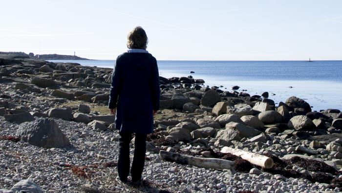En kvinna står och tittar ut över havet.