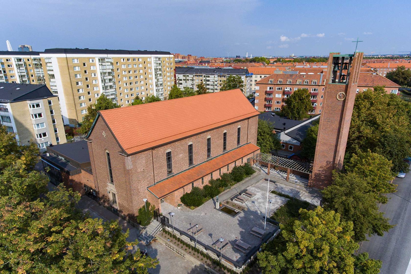 Röd tegelkyrka mitt i ett bostadsområde