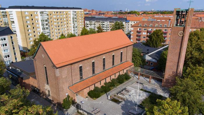 Röd tegelkyrka mitt i ett bostadsområde