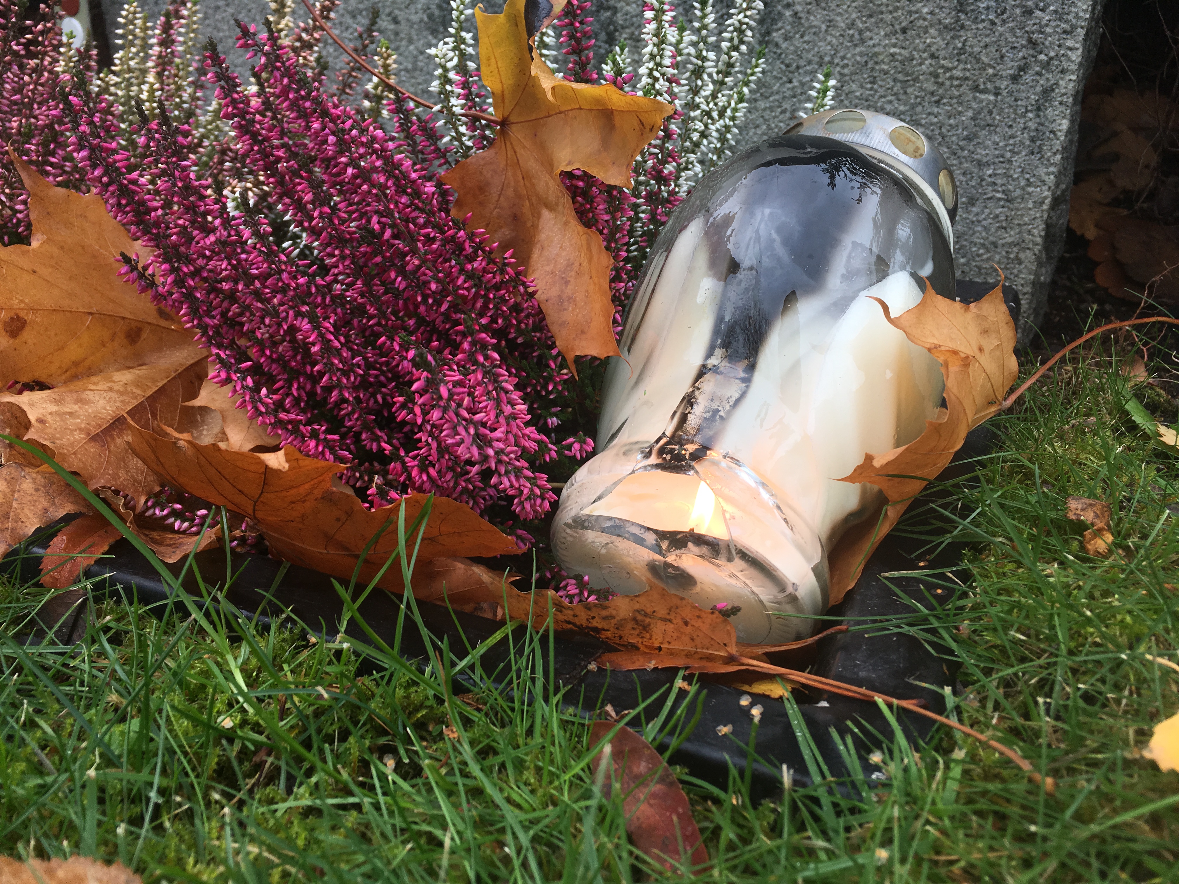Ett gravljus i glasbehållare som spruckit av hettan och orsakat brand på graven