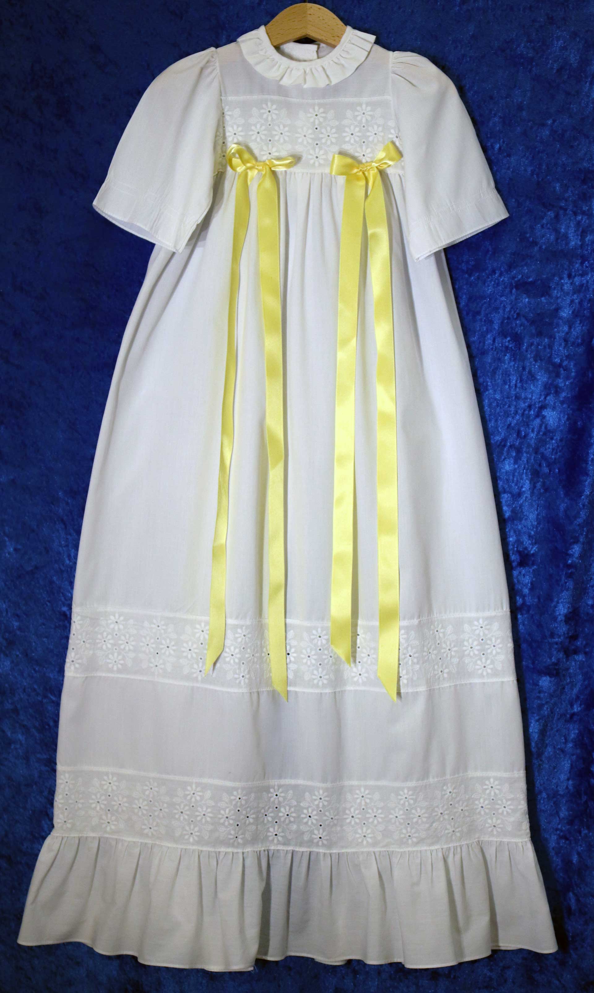 Dopklänning nr 1: Vit dopklänning. Det går att fästa band på klänningen, banden finns i gult, rosa och blått.