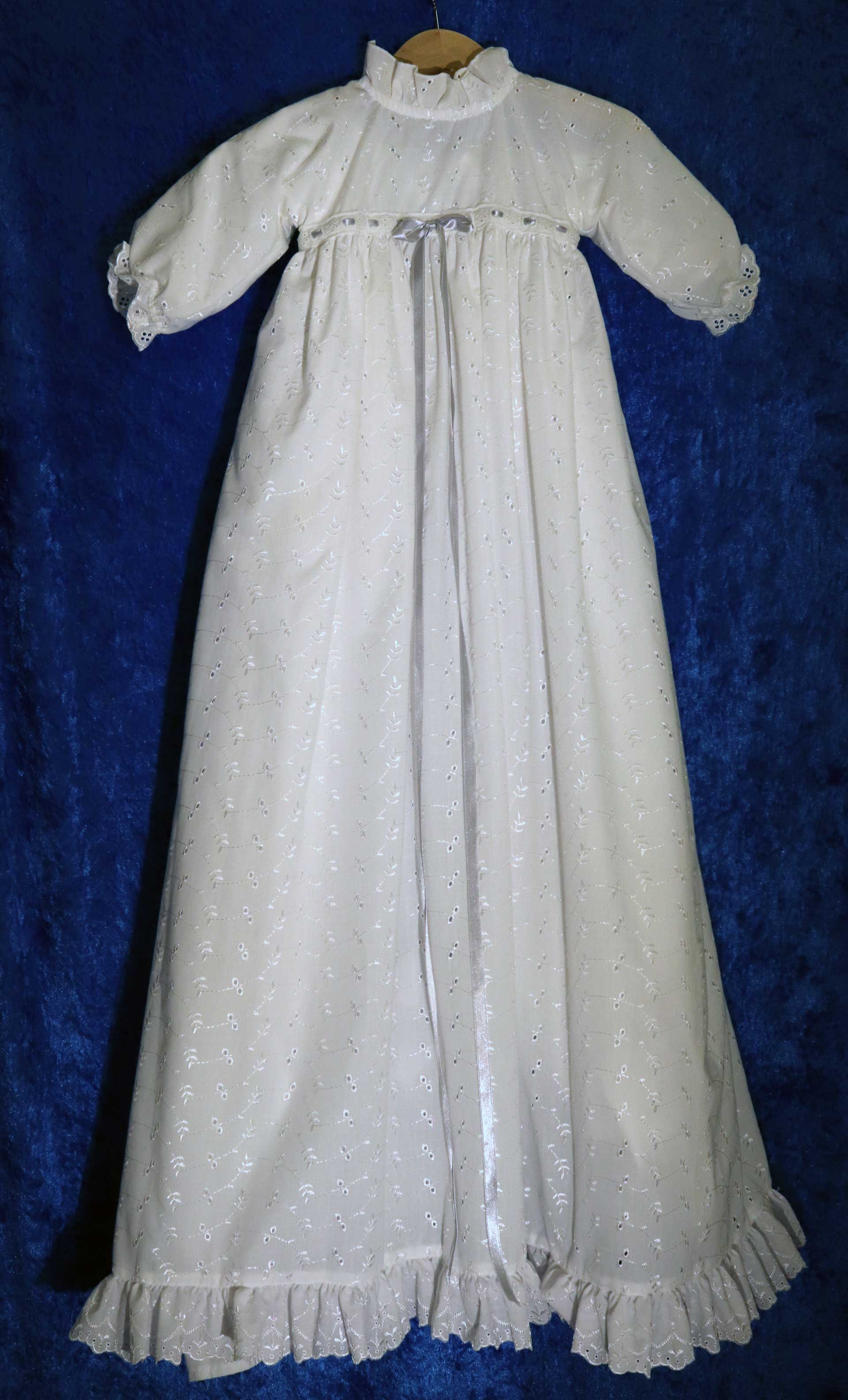 Dopklänning nr 5: Vit dopklänning med slät underklänning och överklänning i brodyr. Det finns band i olika färger att trä i.
