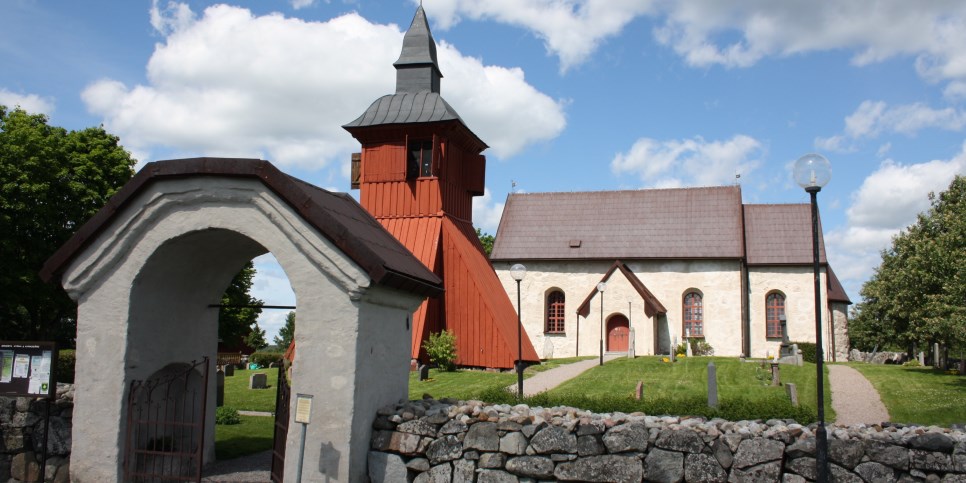 Ett valv,  ett klocktorn och Orkesta kyrkas huvudbyggnad, det är sommar