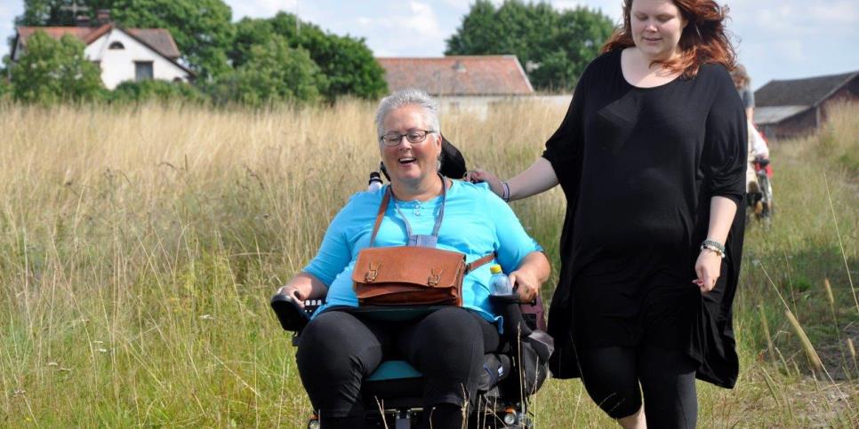 En rullstolsburen kvinna och en gående kvinna i samspråk. 
