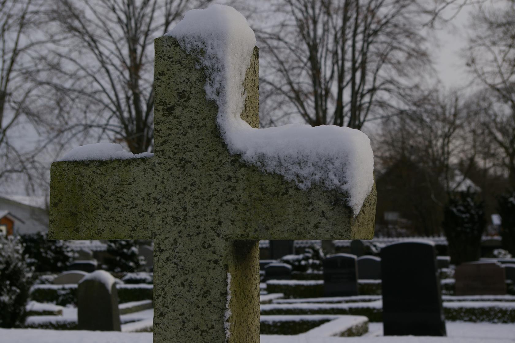 Gravsten format som ett kors i ett snöigt landskap.