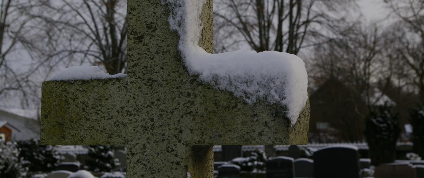 Gravsten format som ett kors i ett snöigt landskap.