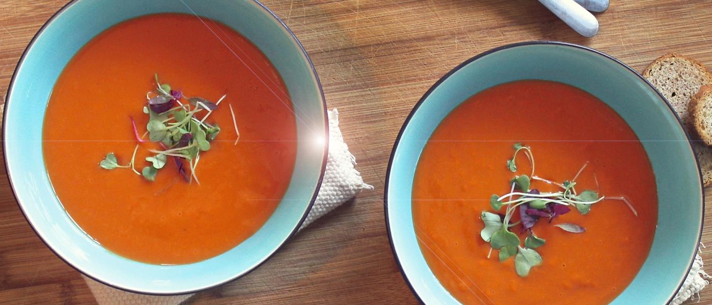 Två blåa tallrikar fyllda med krämig orange soppa.