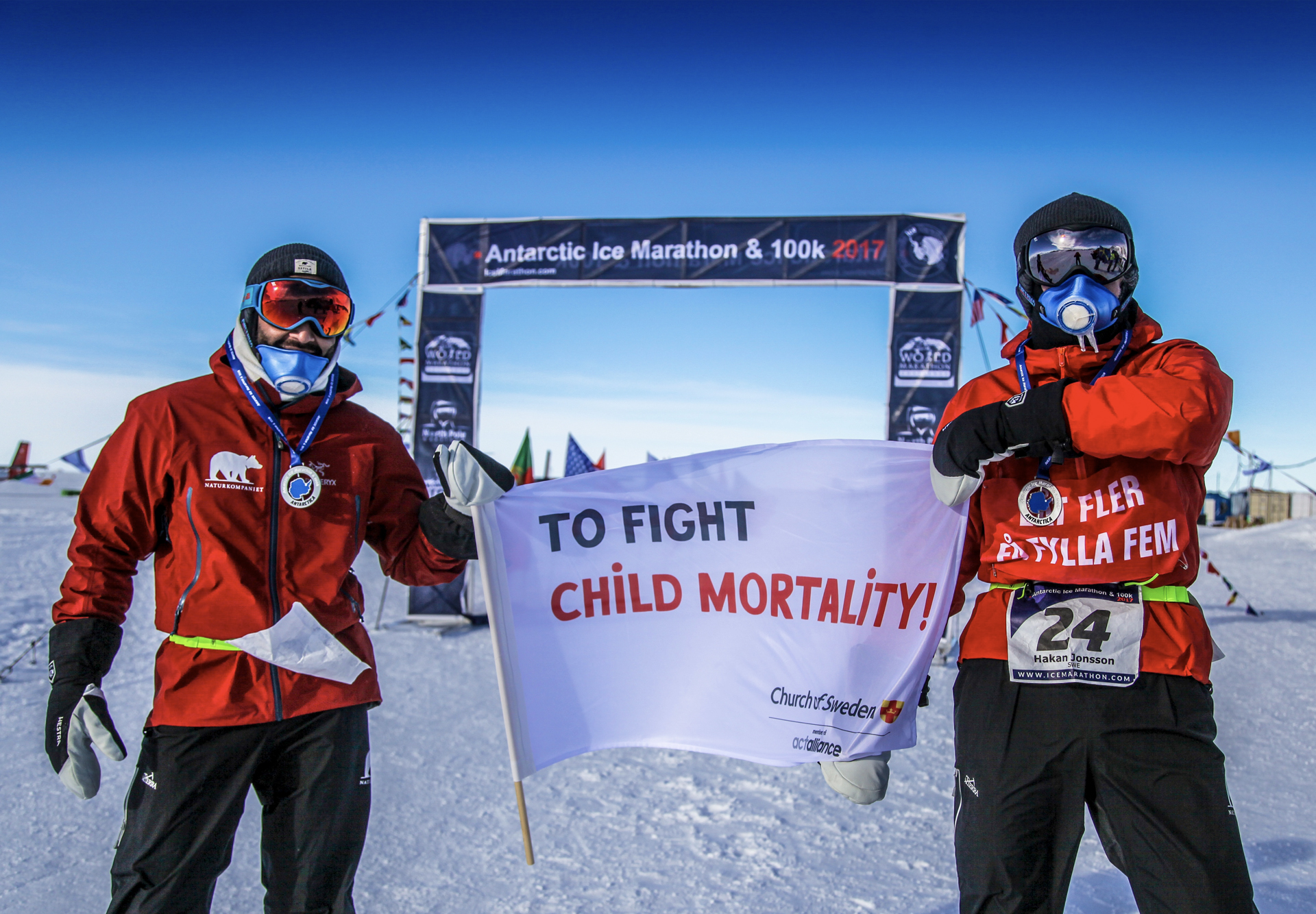 Två män som sprungit maraton håller upp en ACT Svenska kyrkan flagga. 