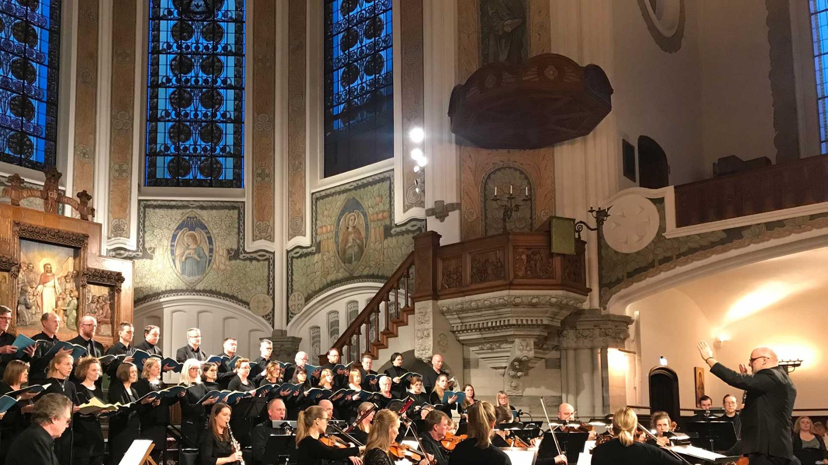 Sankt Johannes kammarkör tillsammans med musiker och dirigent sjunger i koret i S:t Johannes kyrka