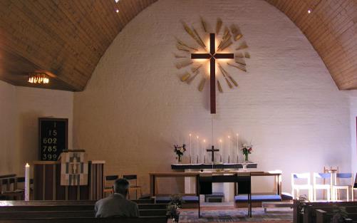 Tullinge kyrka. Altarkors. Tända ljusstakar. Ljus från takfönster