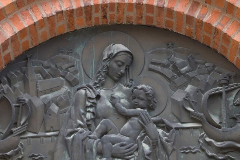 Bronsreliefen över kyrkporten till S:ta Maria kyrka föreställer jungfru Maria och Jesusbarnet. Runt dem ses skepp och stadsmotiv från Ystad. 