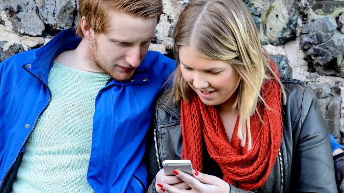 Kille och tjej som tittar på mobiltelfon