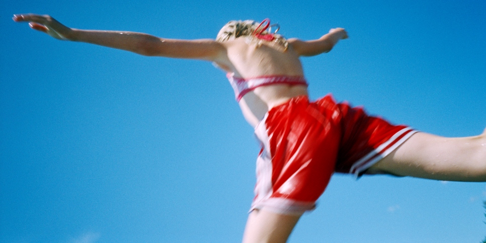 En flicka i baddräkt ser ut att hoppa från en trampolin.