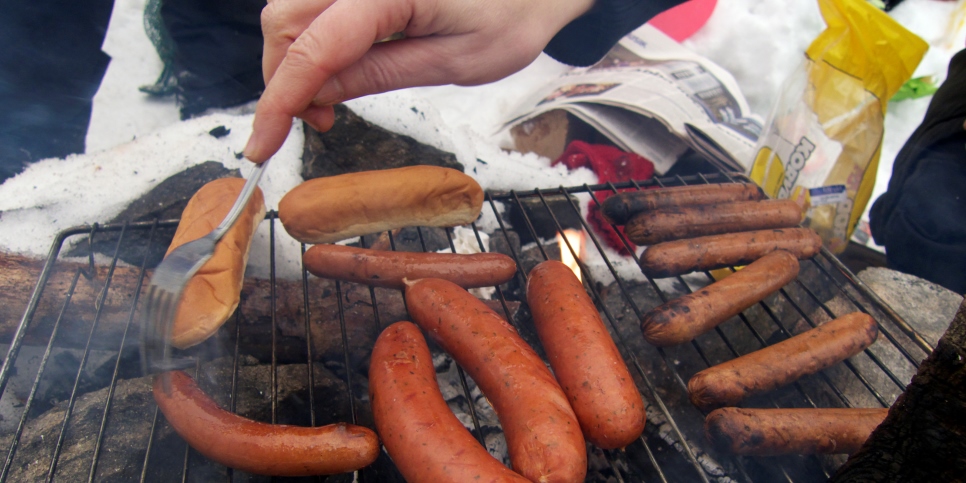 Korvar och korvbröd på ett grillgaller utomhus