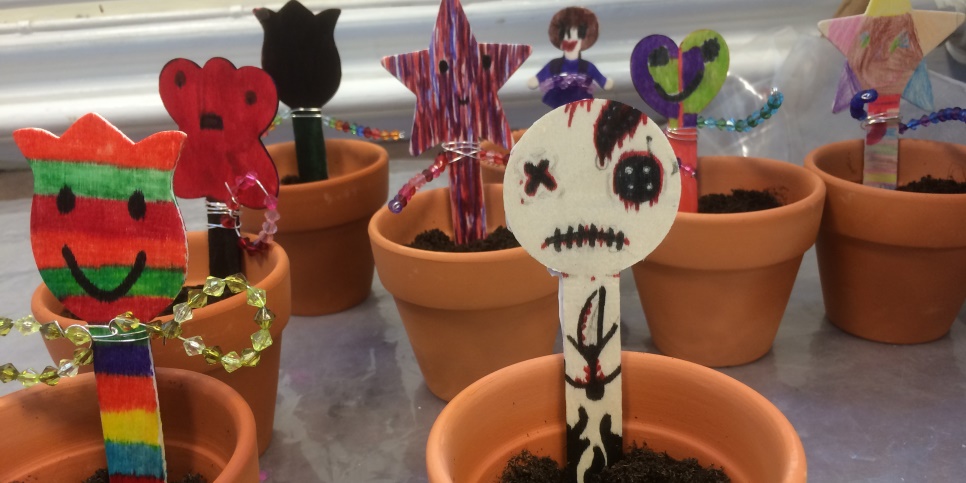 Ett antal krukor med figurer istoppade i jorden i krukorna. 