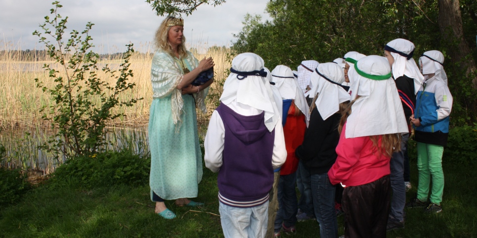 Utomhus, nära strand, pedagog berättar för barn