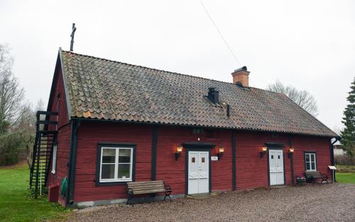 Lundby kapell utvändigt. En rök låg träbyggnad med två vita dörrar och tegeltak.