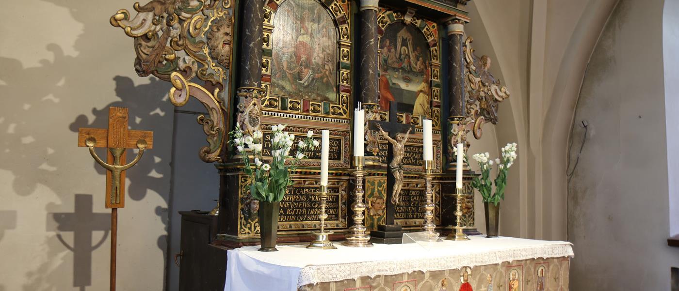 En rikt utsmyckad altaruppsats. Framför denna ses altarbordet med ett vitt antependium.