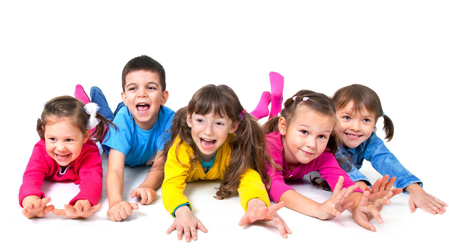 Fem barn med färgglada kläder ligger på ett golv, tittar fram, ler och skrattar. 