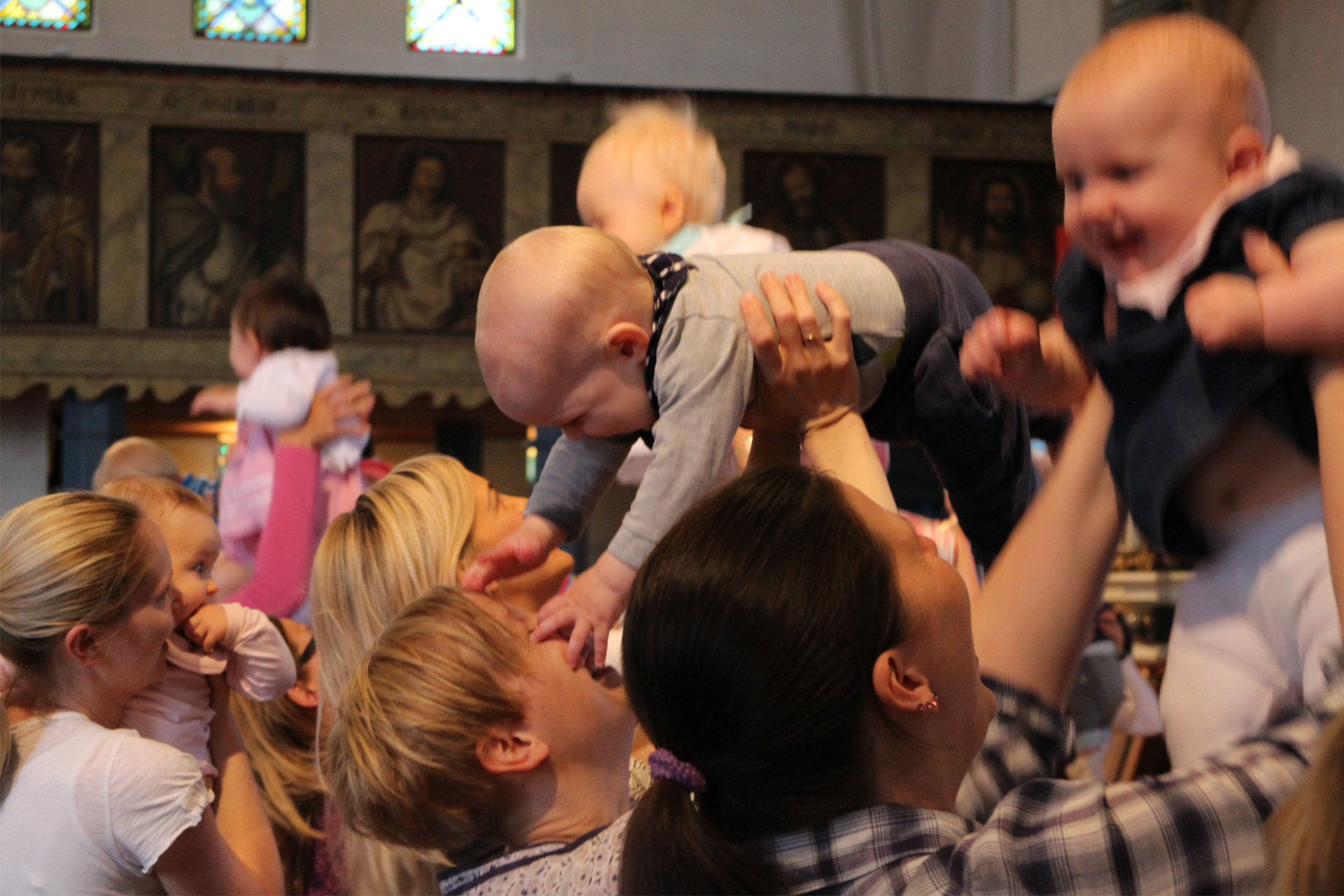 Glada bebisar/barn lyfts upp i luften i kyrka