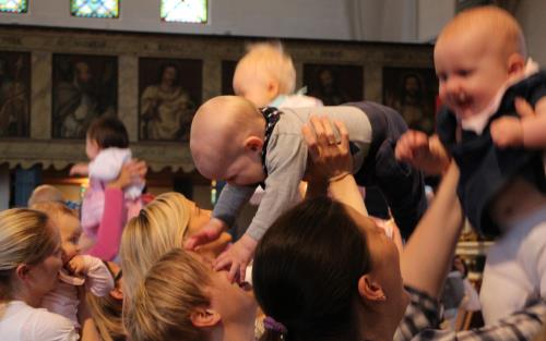 Glada bebisar/barn lyfts upp i luften i kyrka