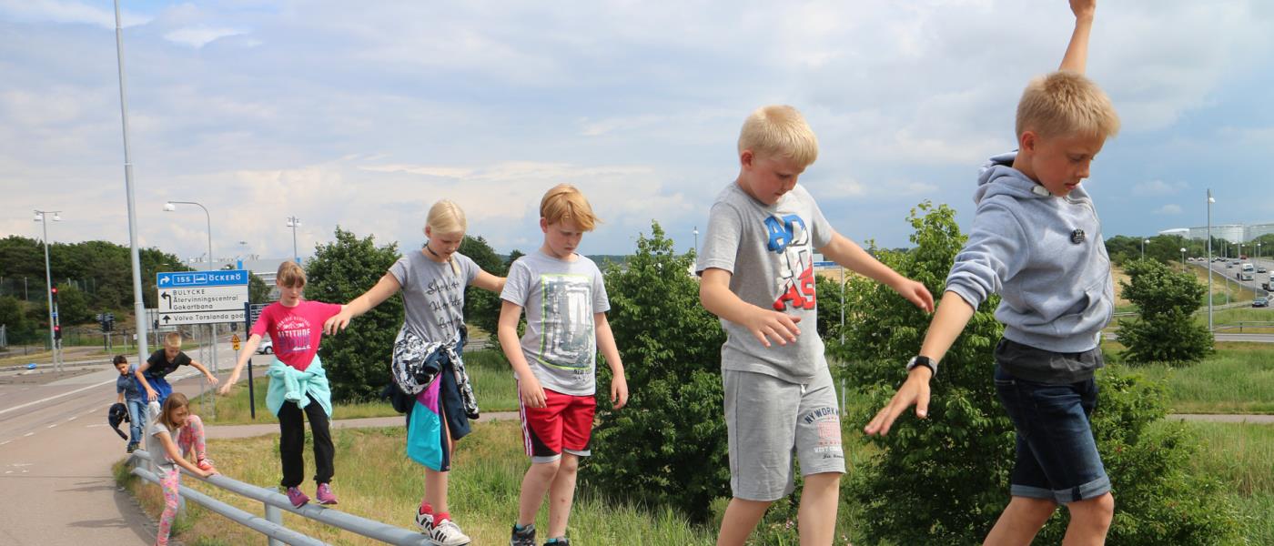 Barn går balansgång på vägräcke