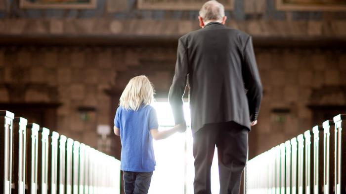 En kyrkgång där ett barn och en gammal person går hand i hand mot dörren