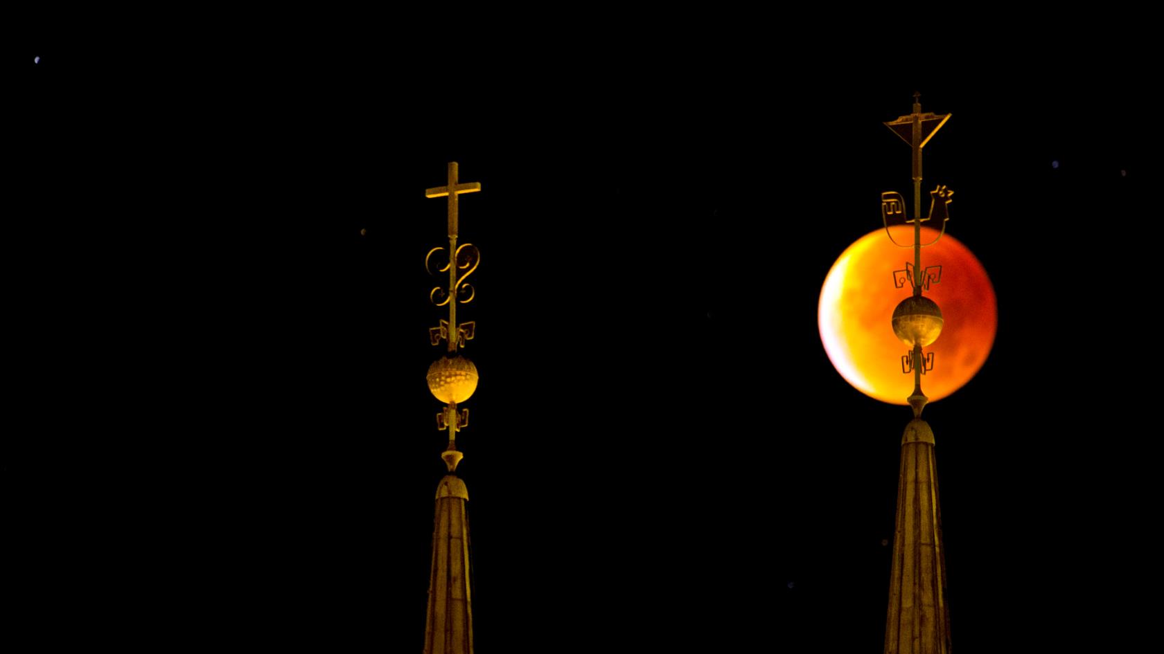 Nattbild på domkyrkans spiror framför en mörkgul måne.