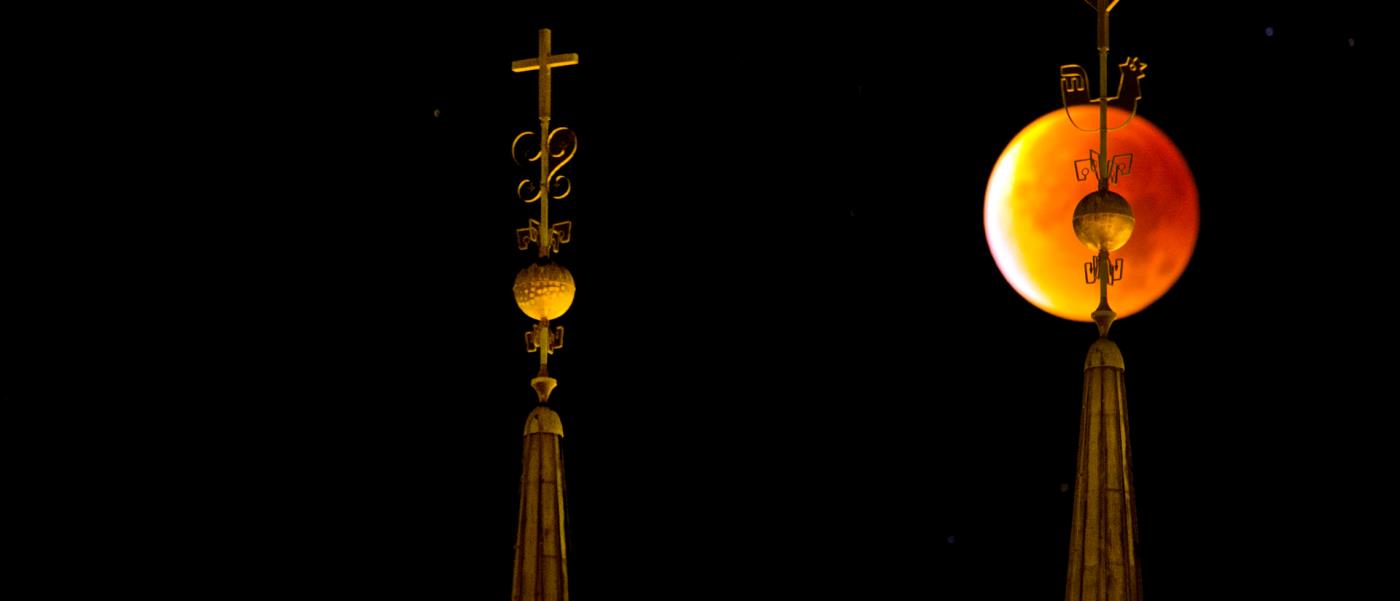 Nattbild på domkyrkans spiror framför en mörkgul måne.
