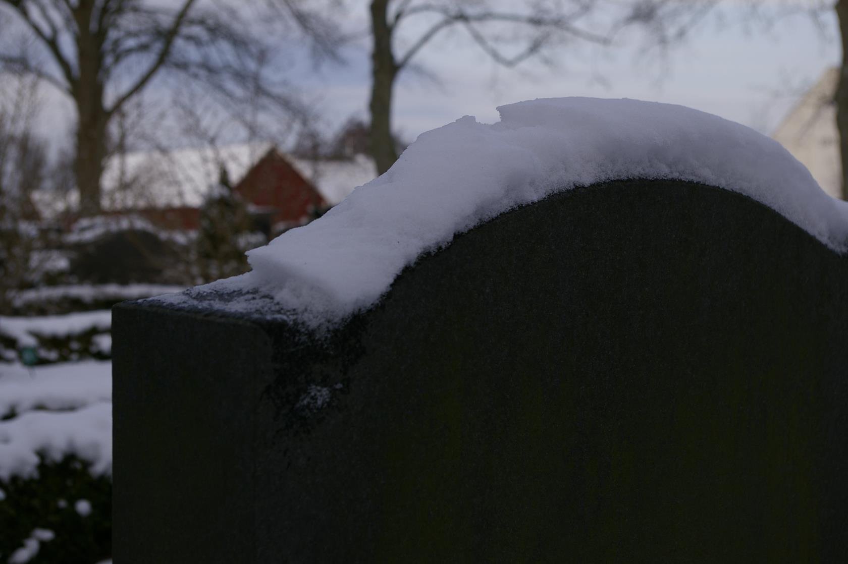 Närbild på en gravsten med snö.