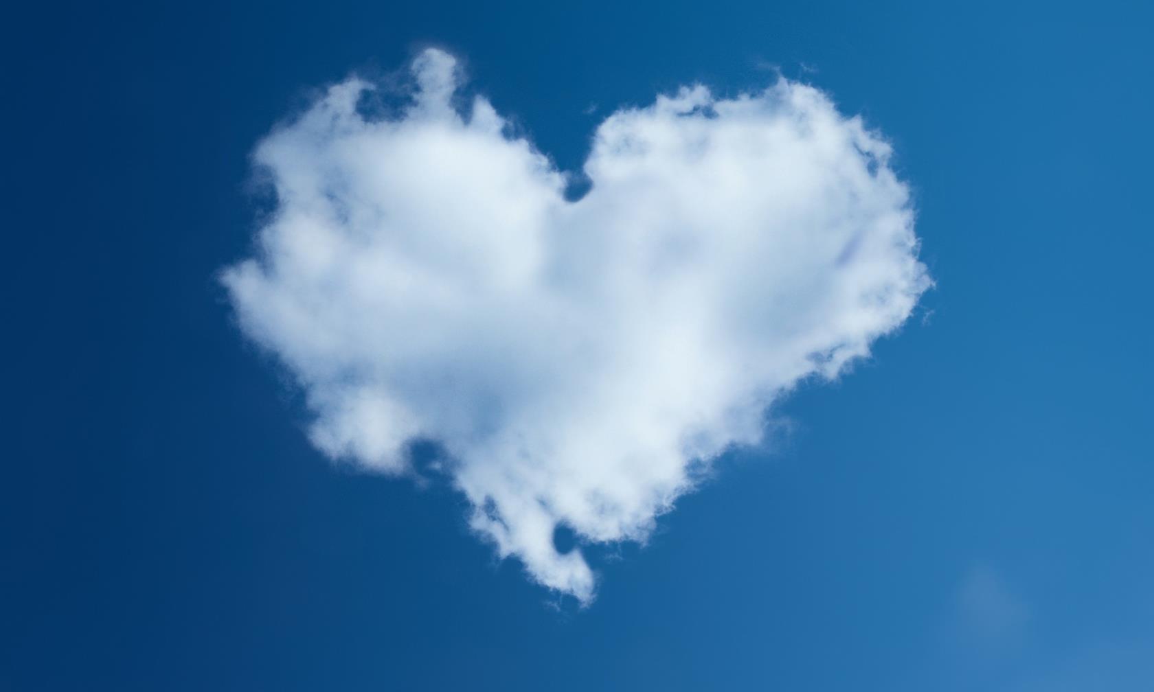 Stort moln i en hjärtform på en blå himmel.