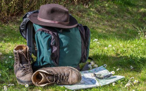 En vandrares utrustning ligger lämnad i gräset. Ryggsäck, kängor, hatt, karta.