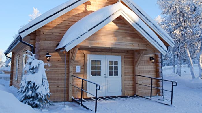 Högvålens kapell en vacker vinterdag. Solen lyser på det snöiga korset ovanför dörren.