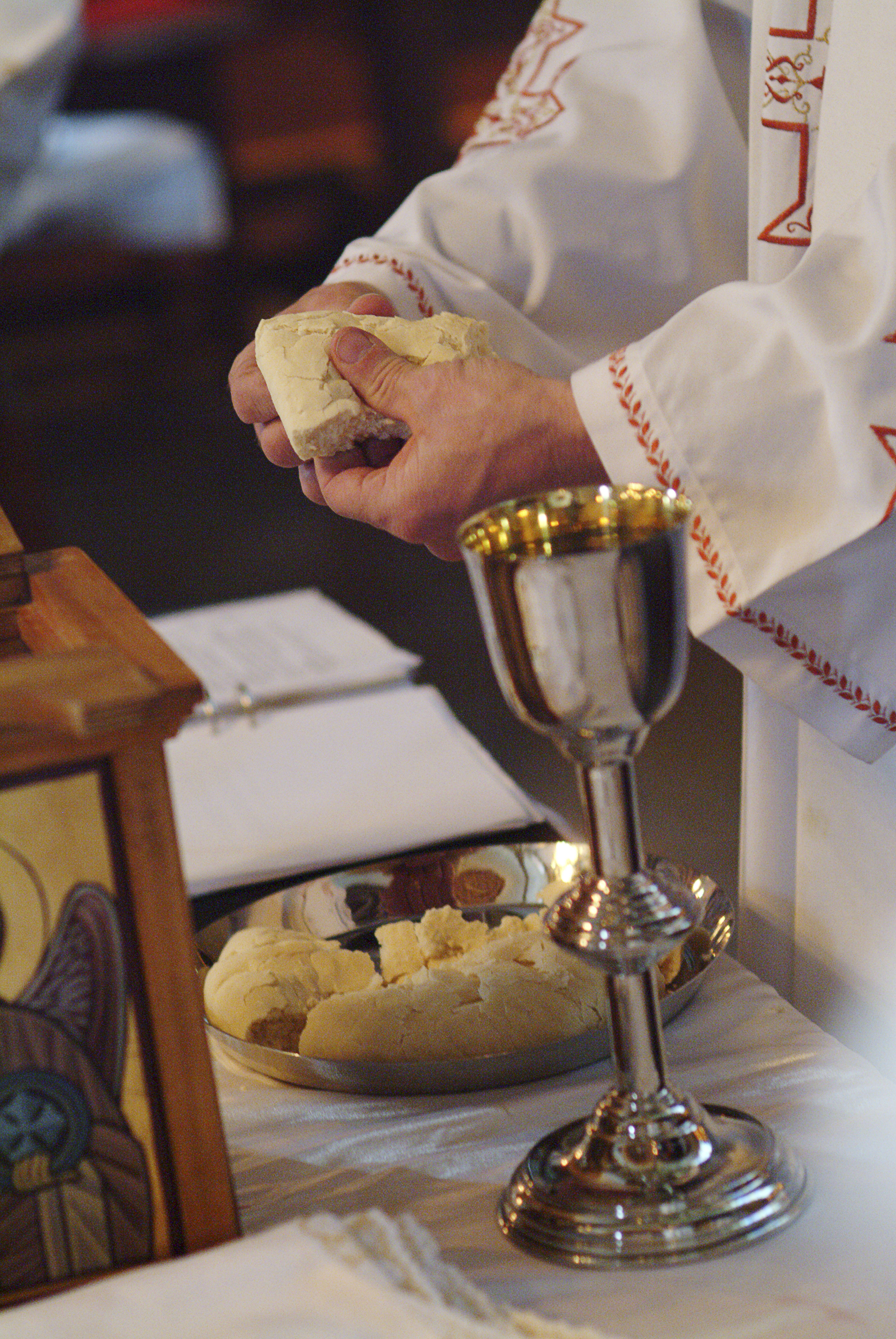 En präst bryter bröd under nattvarden.