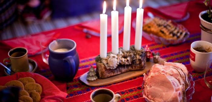 En adventsljusstake med alla ljus tända står på ett julbord.