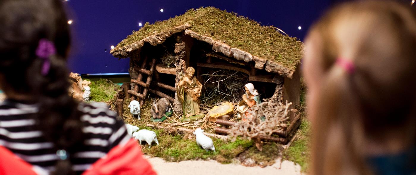 Två flickor står och tittar på en julkrubba.
