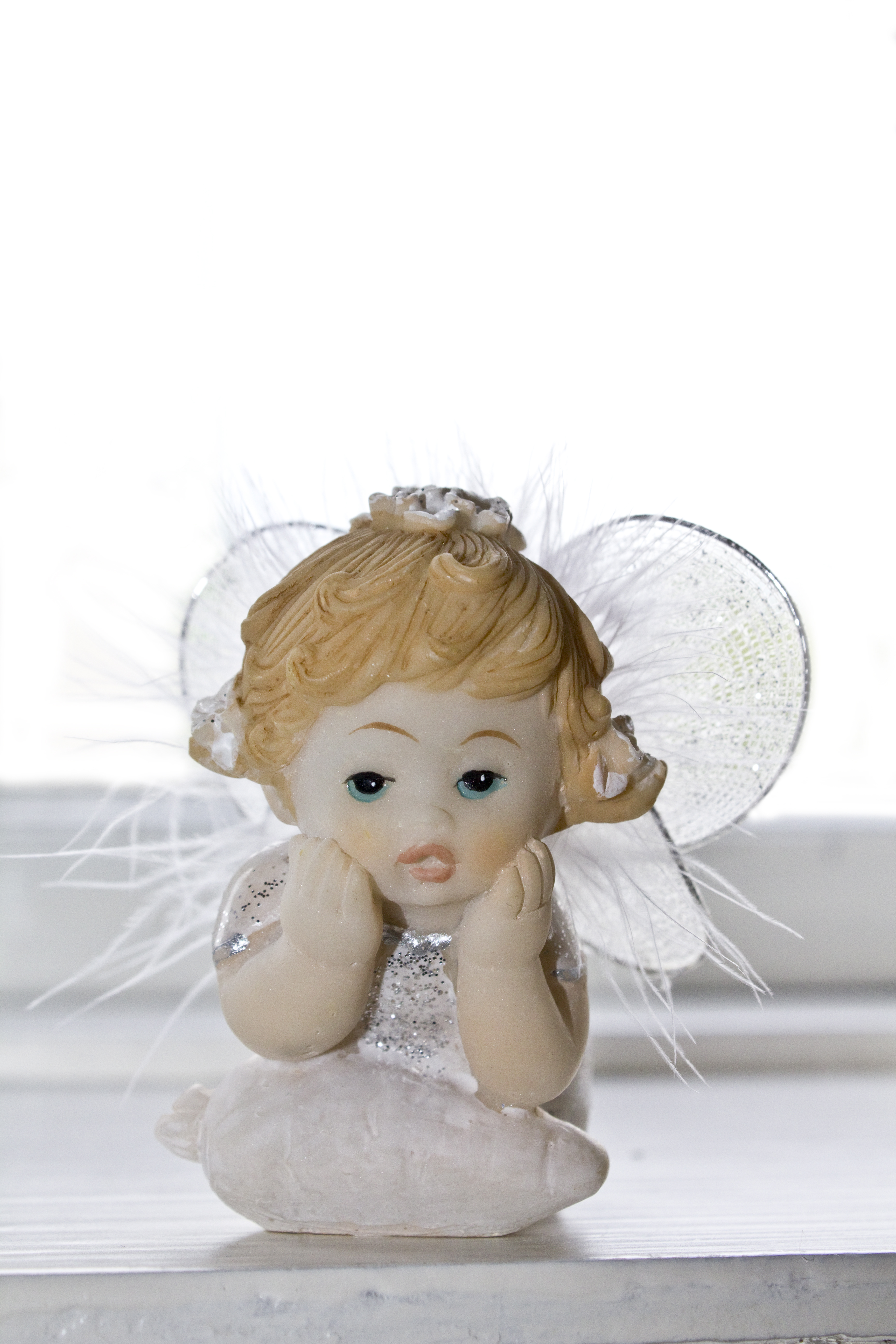 En liten prydnadsängel i ett fönster.