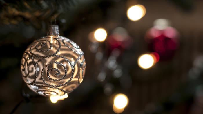 En julgranskula med glittriga detaljer hänger i granen.