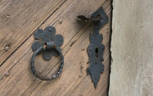 En portklapp och ett nyckelhål på en gammal trädörr.