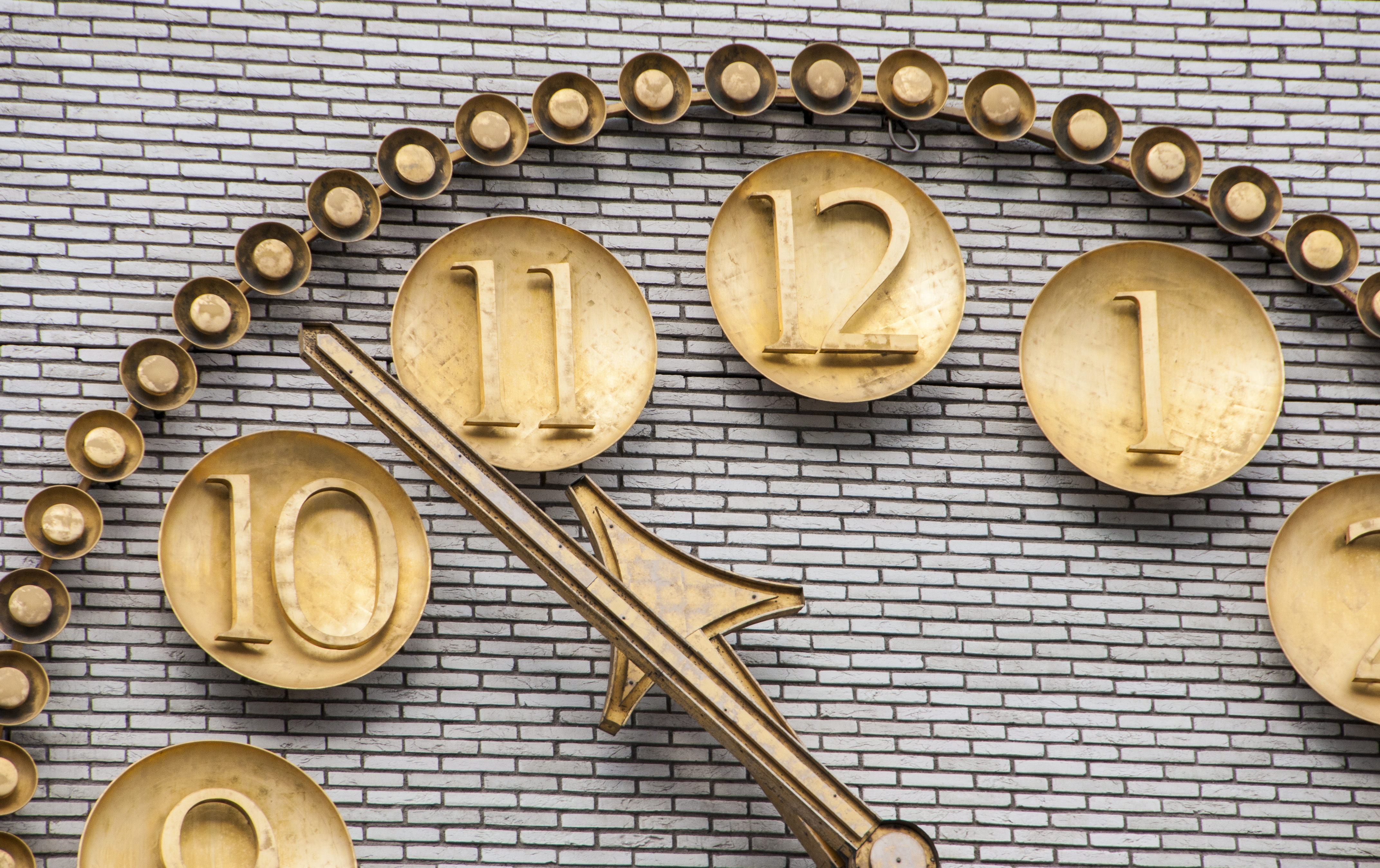 En stor guldig urtavla på en tegelvägg.