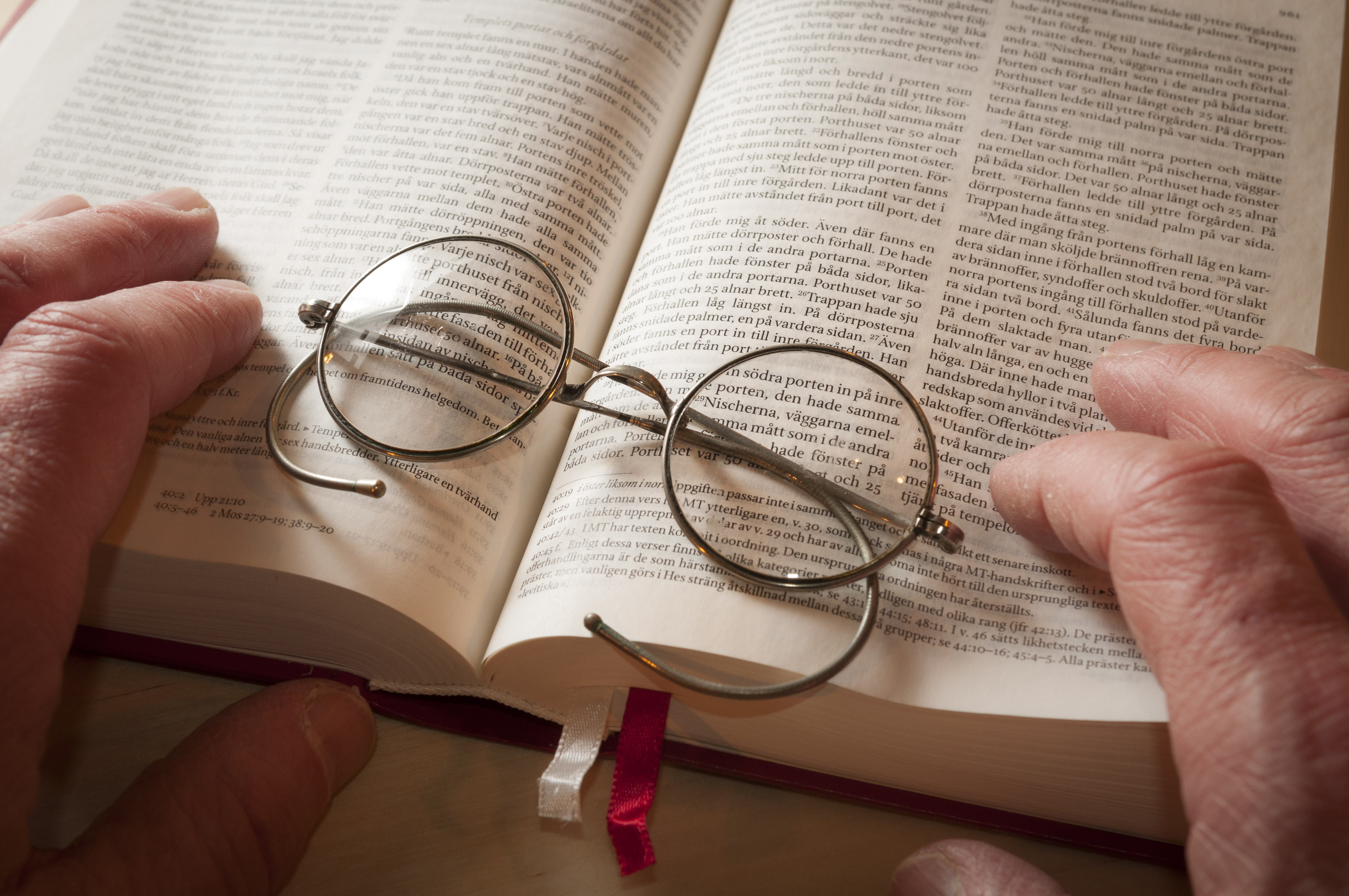 Närbild på ett par runda glasögon som ligger i en bibel.