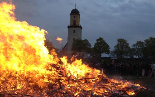 En stor majbrasa och en kyrka i bakgrunden.