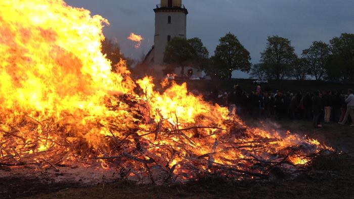 En stor majbrasa och en kyrka i bakgrunden.