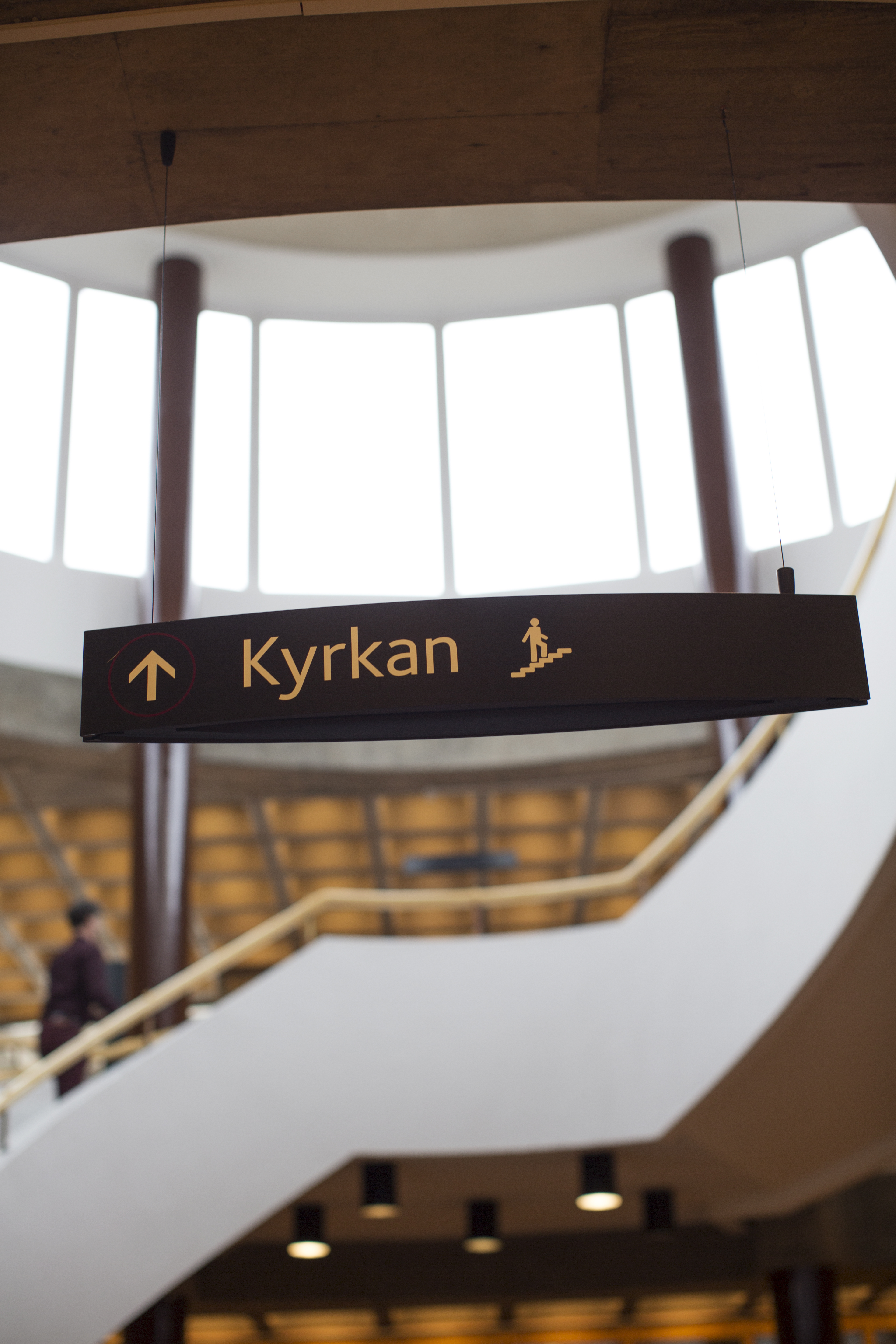 En skylt med texten Kyrkan och en pil uppåt. En trappa i bakgrunden.
