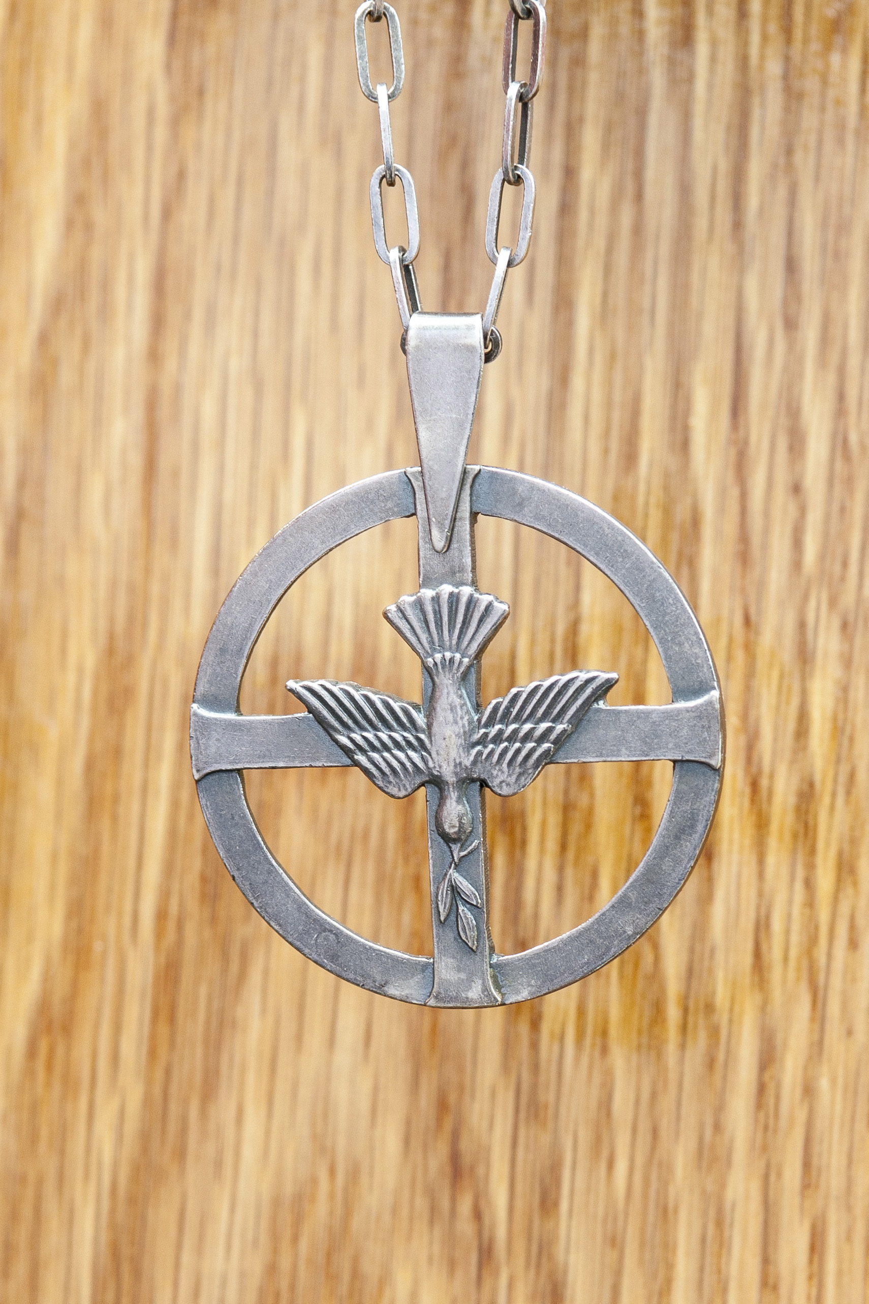 Ett halsband med ett diakonemblem mot träbakgrund.