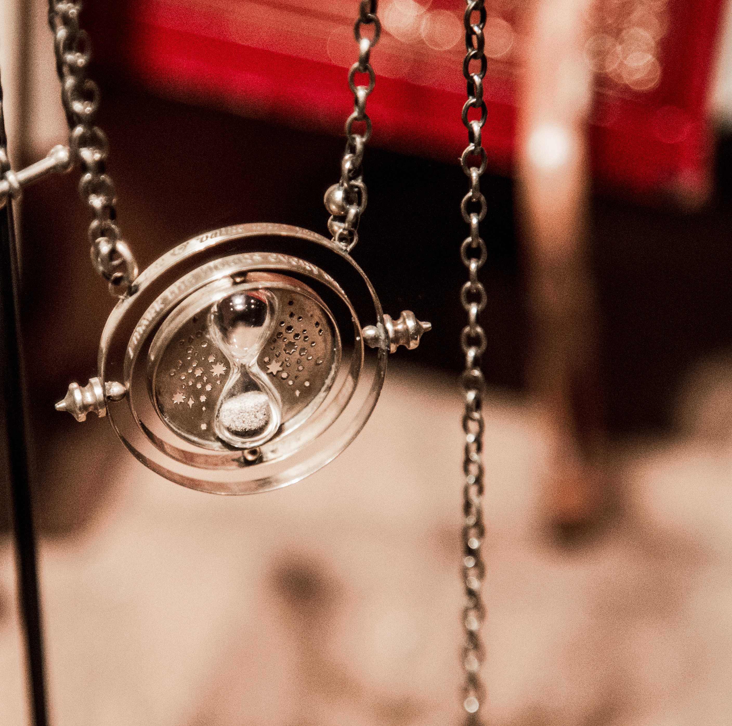 En kedja med ett runt glassmycke med ett timglas i mitten.