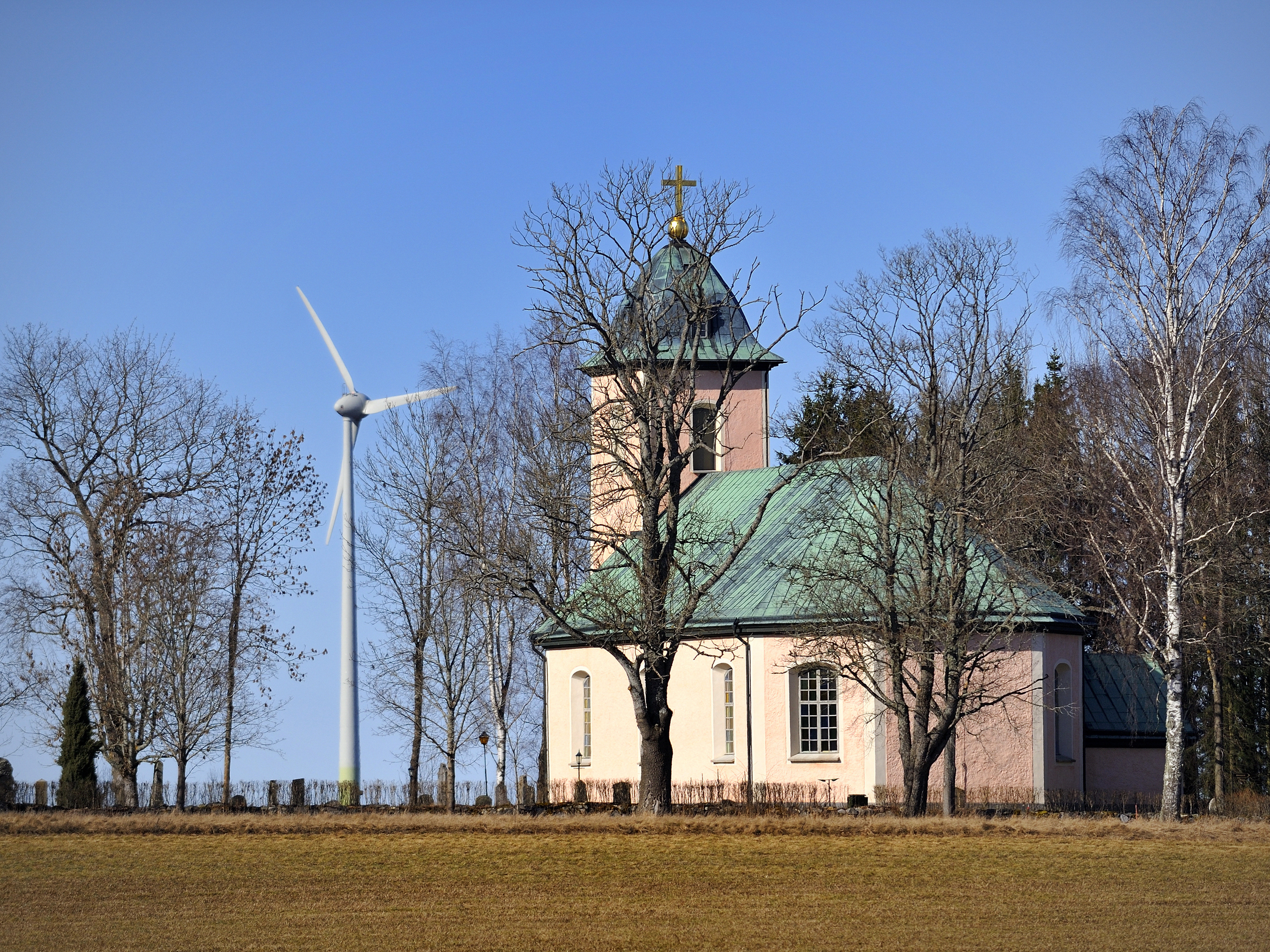 Ett vindkraftverk står utanför en kyrka.