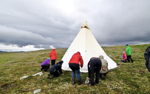 En grupp människor sätter upp ett tält på fjället.