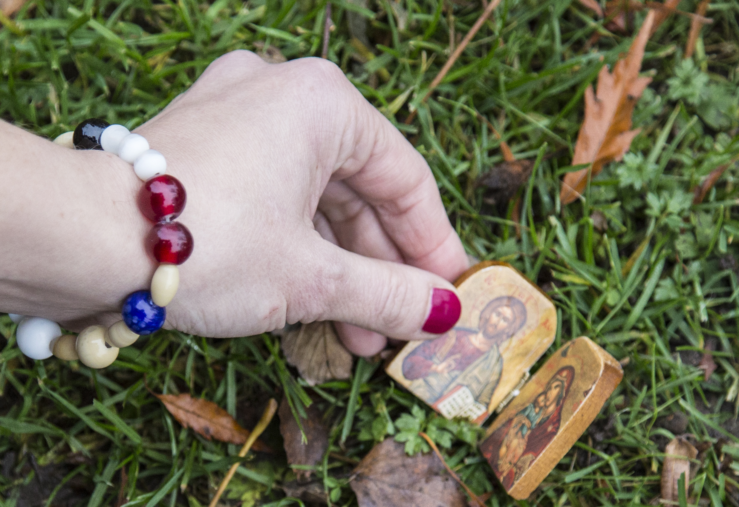 Närbild på någon som lägger en liten träbit med ikonbilder i gräset.