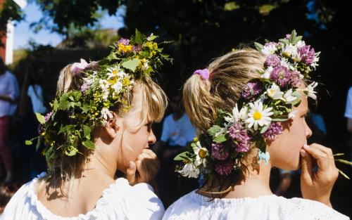 Två små flickor i vita klänningar och midsommarkransar.